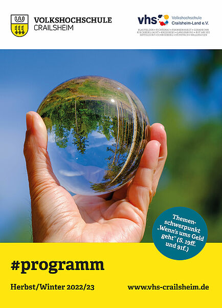 Titelseite Programm vhs Crailsheim Herbst/Winter 2022/23 (Glaskugel mit Landschaft auf dem Kopf in einer Hand)