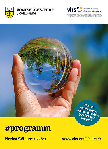 Titelseite Programm vhs Crailsheim Herbst/Winter 2022/23 (Glaskugel mit Landschaft auf dem Kopf in einer Hand)