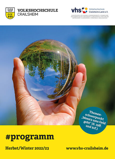 Titelseite Programm vhs Crailsheim Herbst/Winter 2022/23 (Glaskugel mit Landschaft auf dem Kopf in einer Hand)