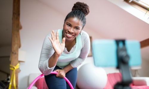 Kategoriebild Hybrid-Kurse - Frau nimmt per Handy am Sportkurs teil (Symbolfoto)