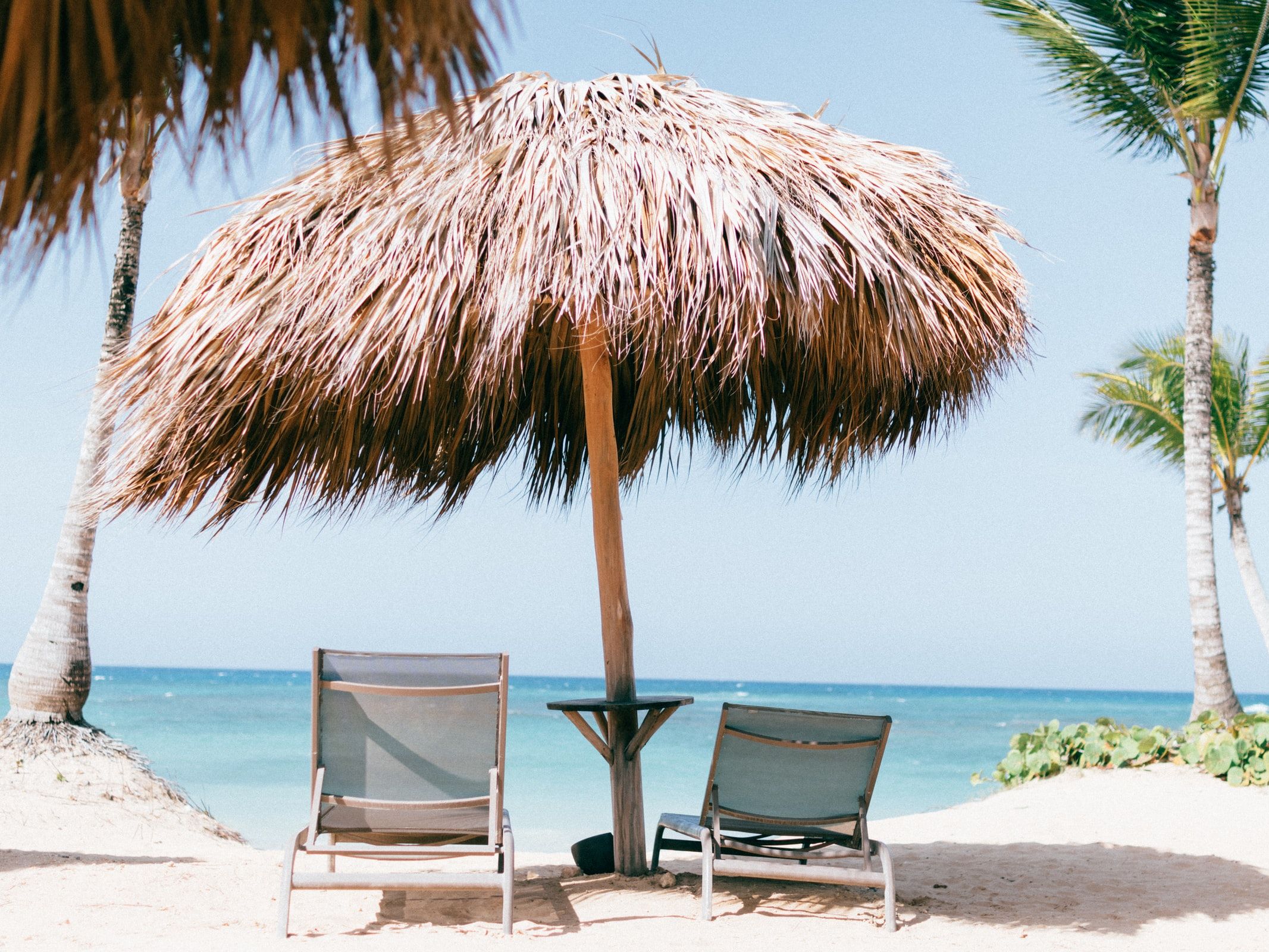 Foto: Liegestühle unter Sonnenschirm am Strand
