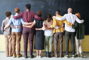 Gruppe Menschen von hinten aus verschiedenen Nationen vor Schultafel