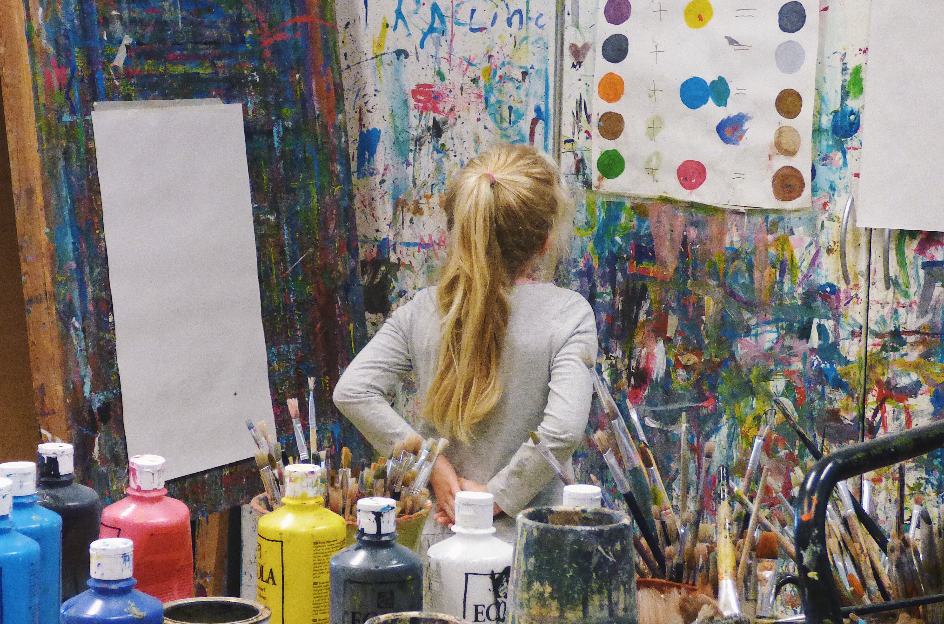 Kind im Kunstatelier mit verschiedenen Farben und Bilderwänden (Symbolfoto)